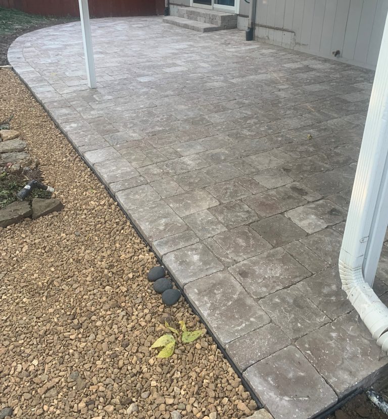 Paver patio beside a house, with a contrasting border.